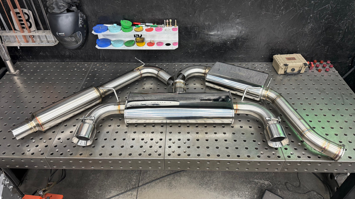 Brockett Built Stealth cat-back exhaust for the Mk7 and Mk7.5 GTI on the fixture table, 3 inch dual exit with Jones tips