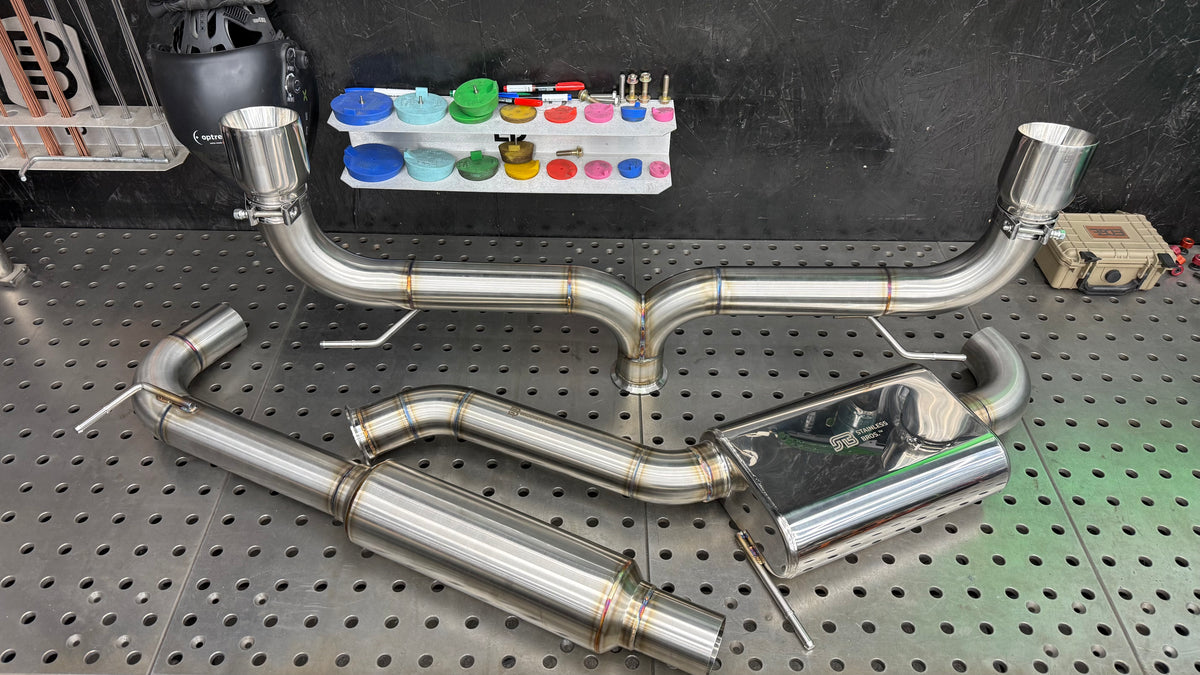 Mk7 and Mk7.5 GTI Aggressive cat-back exhaust laid out on the fixture table, resonator, center muffler and dual exit with Jones tips