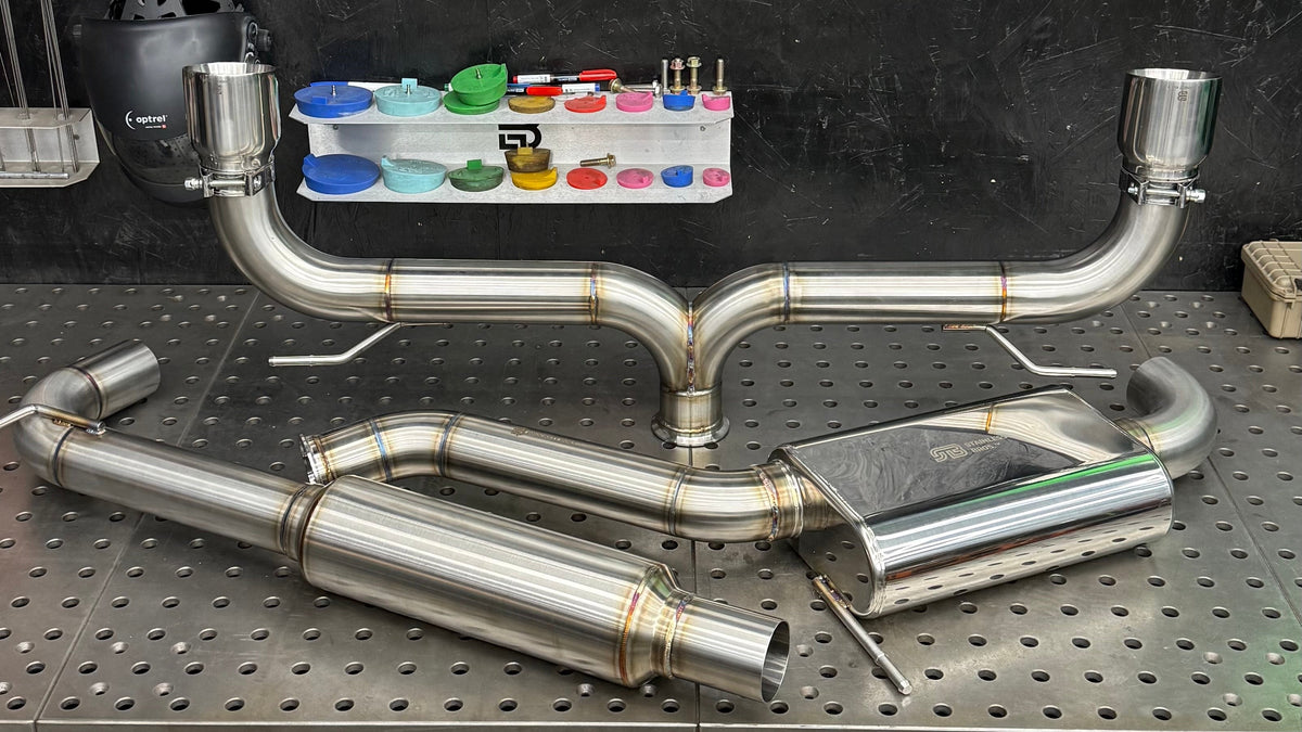 Brockett Built Aggressive cat-back exhaust for the Mk7 and Mk7.5 GTI on the fixture table, 3 inch dual exit with Jones tips and no rear muffler
