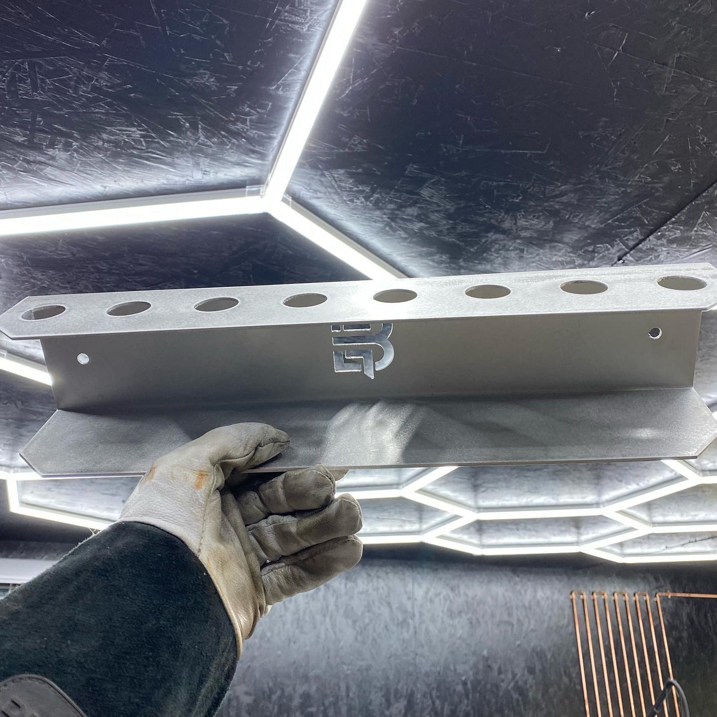 Filler rod bracket mounted on shop wall with welding rods stored